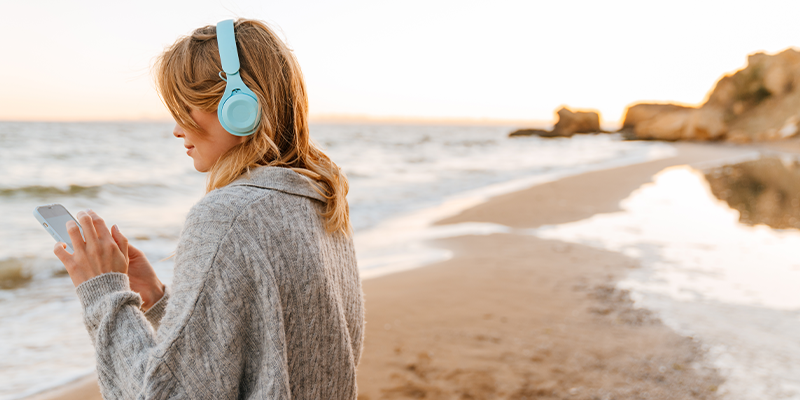 lady with headphones and phone on the beach