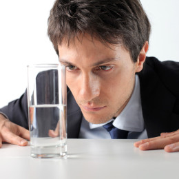 man staring at a half glass of water