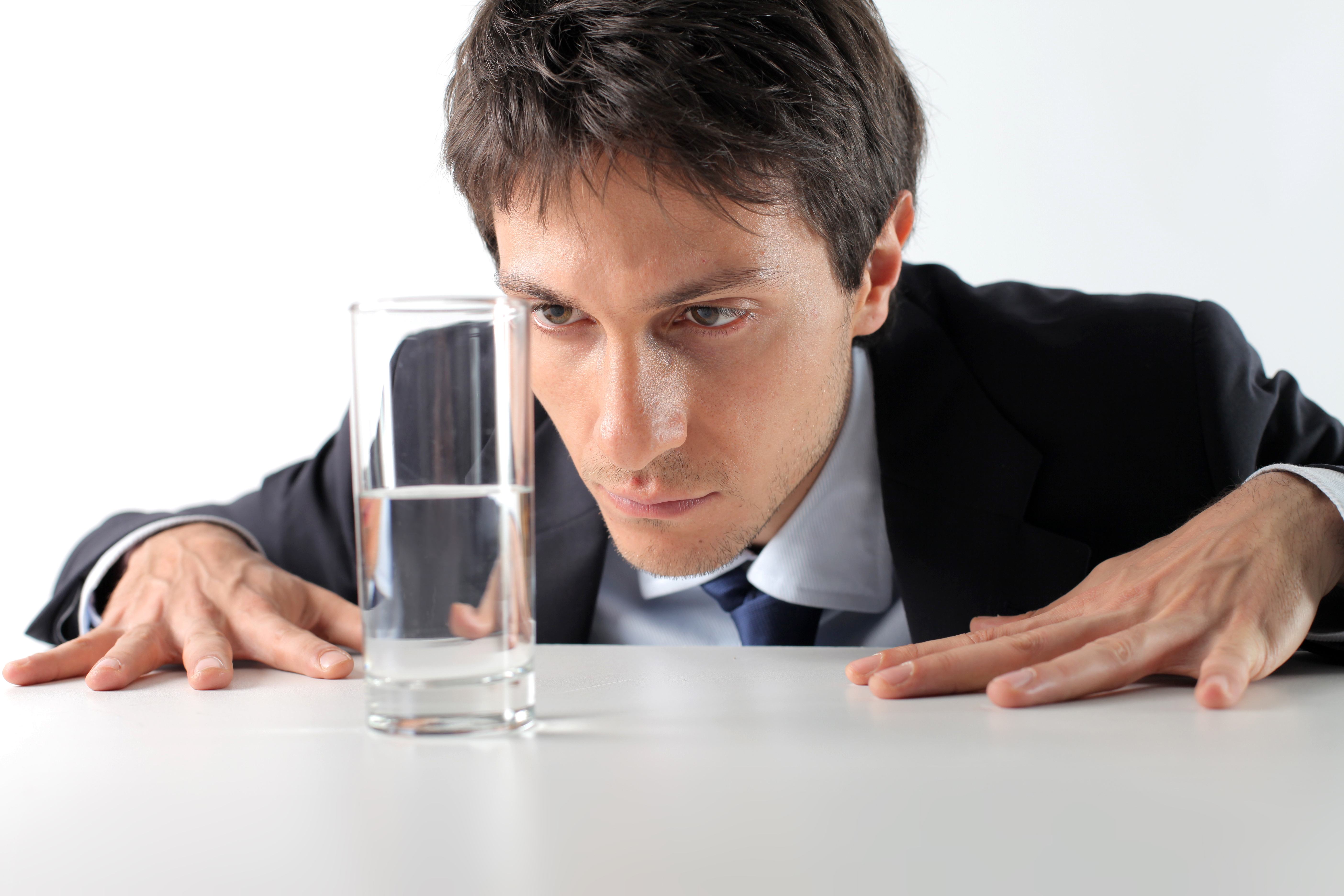 man staring at a half glass of water