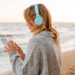 lady with headphones and phone on the beach